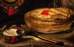 Thin pancakes with caviar and a wooden spoon for Maslenitsa