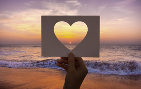 Paper heart against the background of the sea at sunset