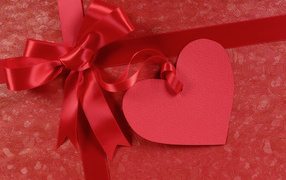 Paper heart with satin ribbon bow on red background