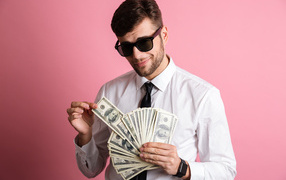 Business man in black glasses with a wad of money on a pink background