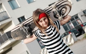 Девочка в полосатом платье со скейтбордом в руках