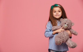 Little girl with a toy on a pink background