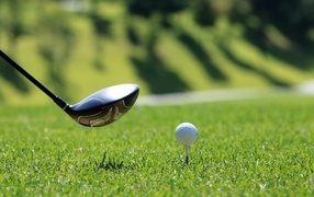 Мяч и клюшка для гольфа на зеленой траве