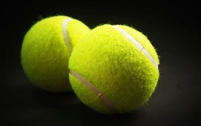 Two yellow tennis balls on a gray background