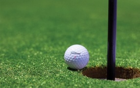 White golf ball lies at the hole