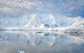 Заснеженные горы под белыми облаками у океана, Антарктида 