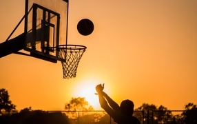 Shooting a basketball hoop at sunset