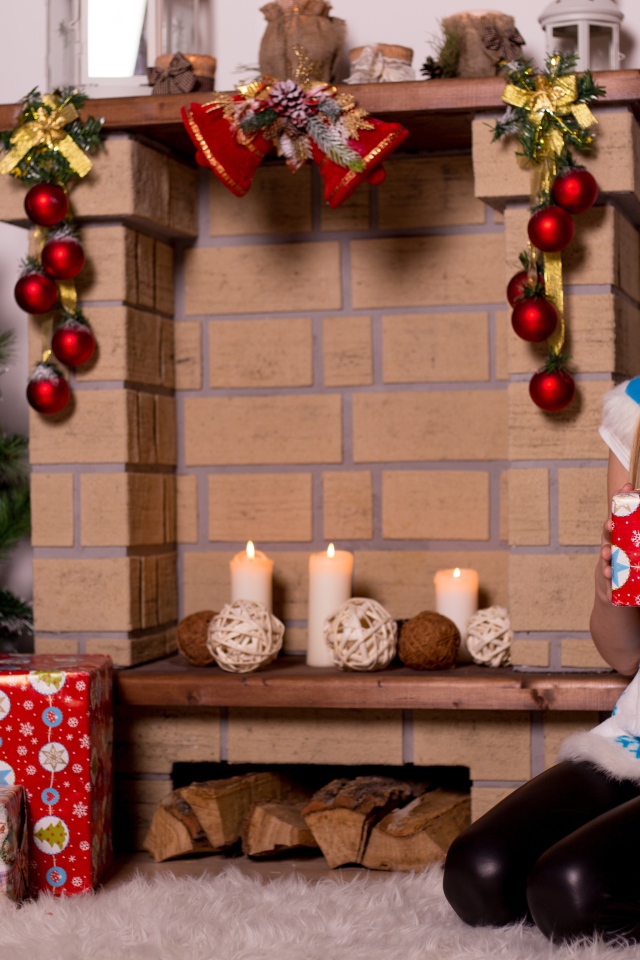 Girl sitting by the fireplace with a gift for the new year